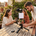 Jóvenes adultos grabando contenido en una terraza con un kit de trípode, luz LED y micrófono