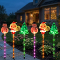 Luces solares navideñas con figuras de muñeco de nieve, Santa Claus y árbol en un jardín al atardecer